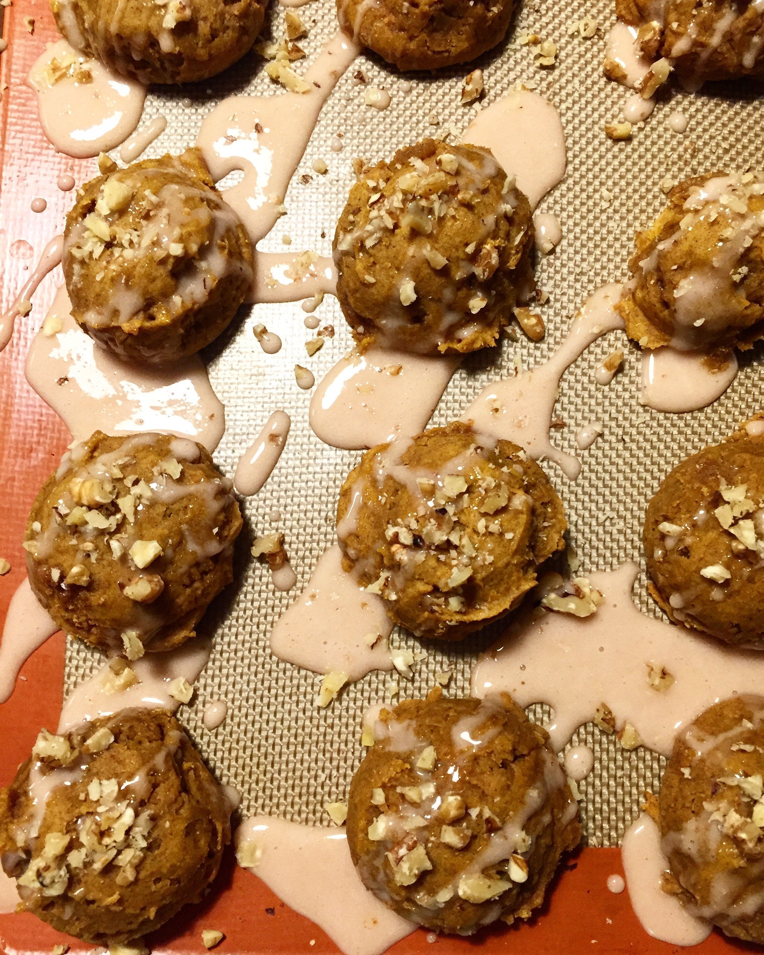 gluten free cookies in a grid on a silicon mat drizzled with a pumpkin spice glaze