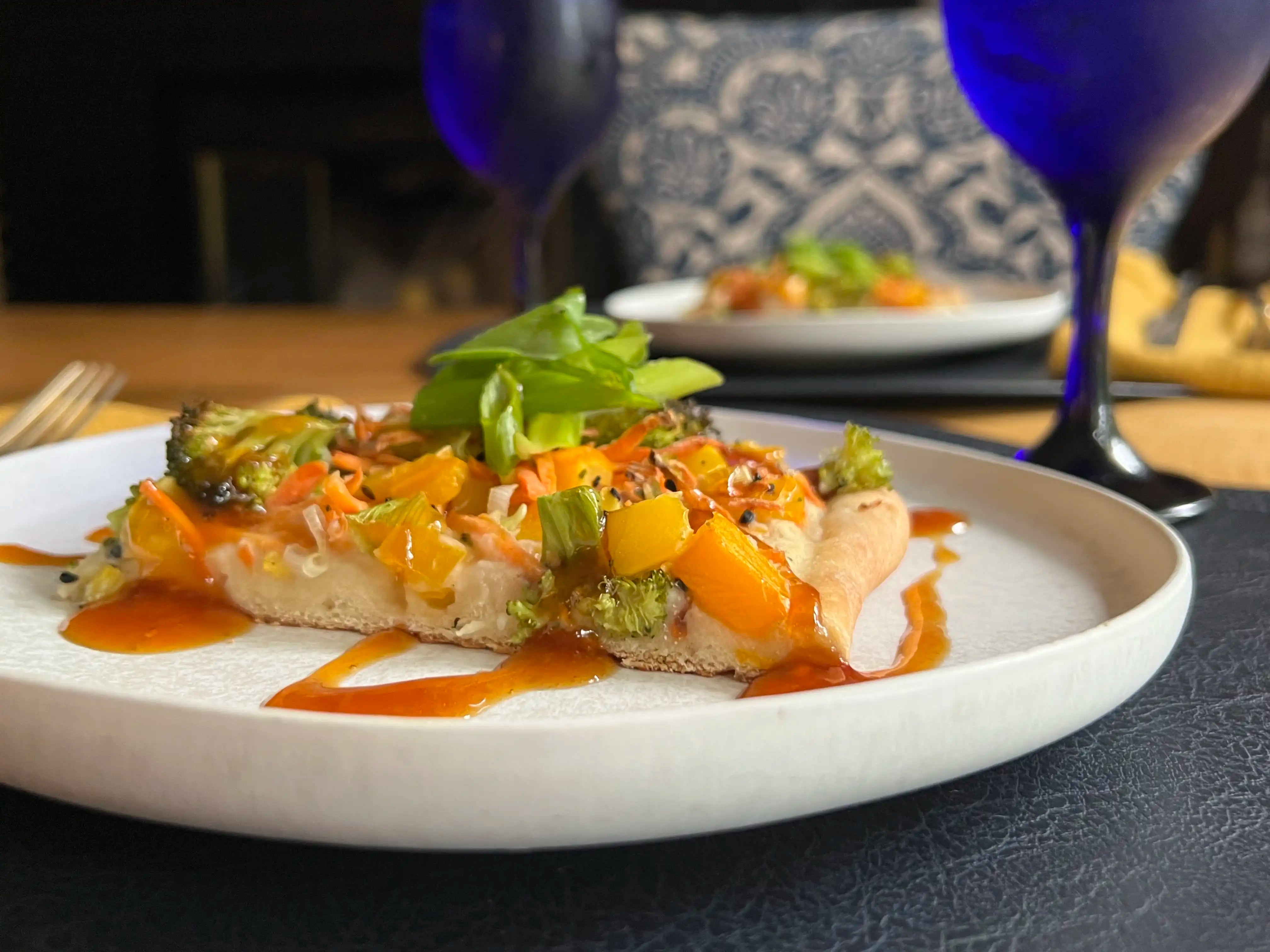 honey garlic sauce drizzled over a vegetable flatbread on a white plate