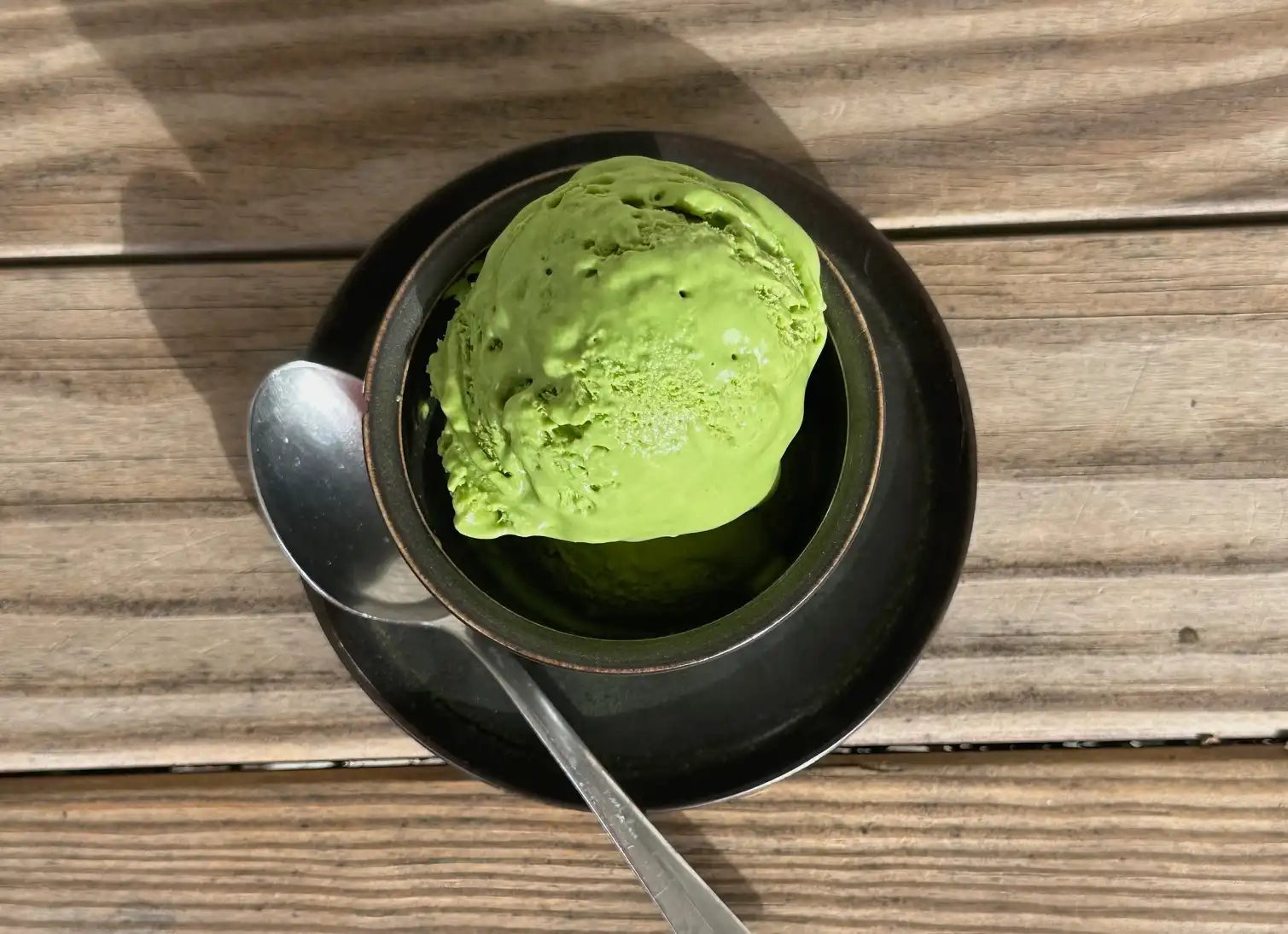 scoop of matcha ice cream in a black cup 