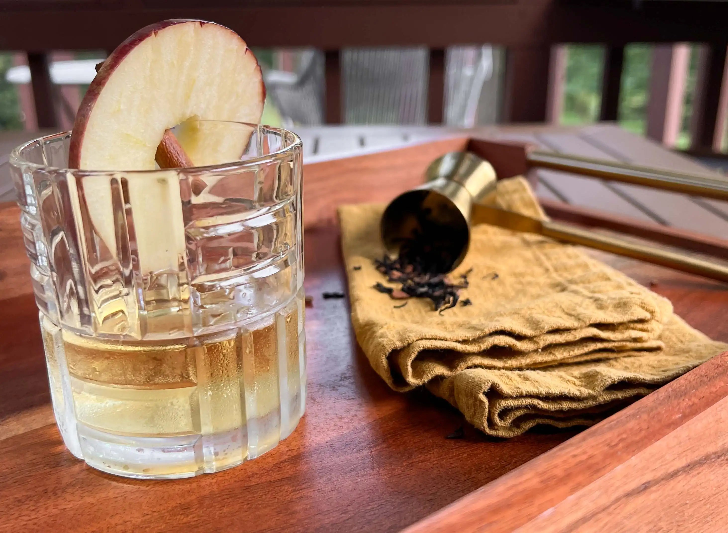 appleteani martini cocktail in a rocks glass with an apple wheel and cinnamon stick garnish