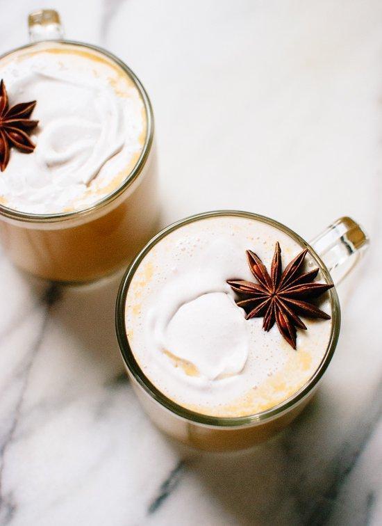 two glass mugs of chai lattes with star anise garnish on a marble background