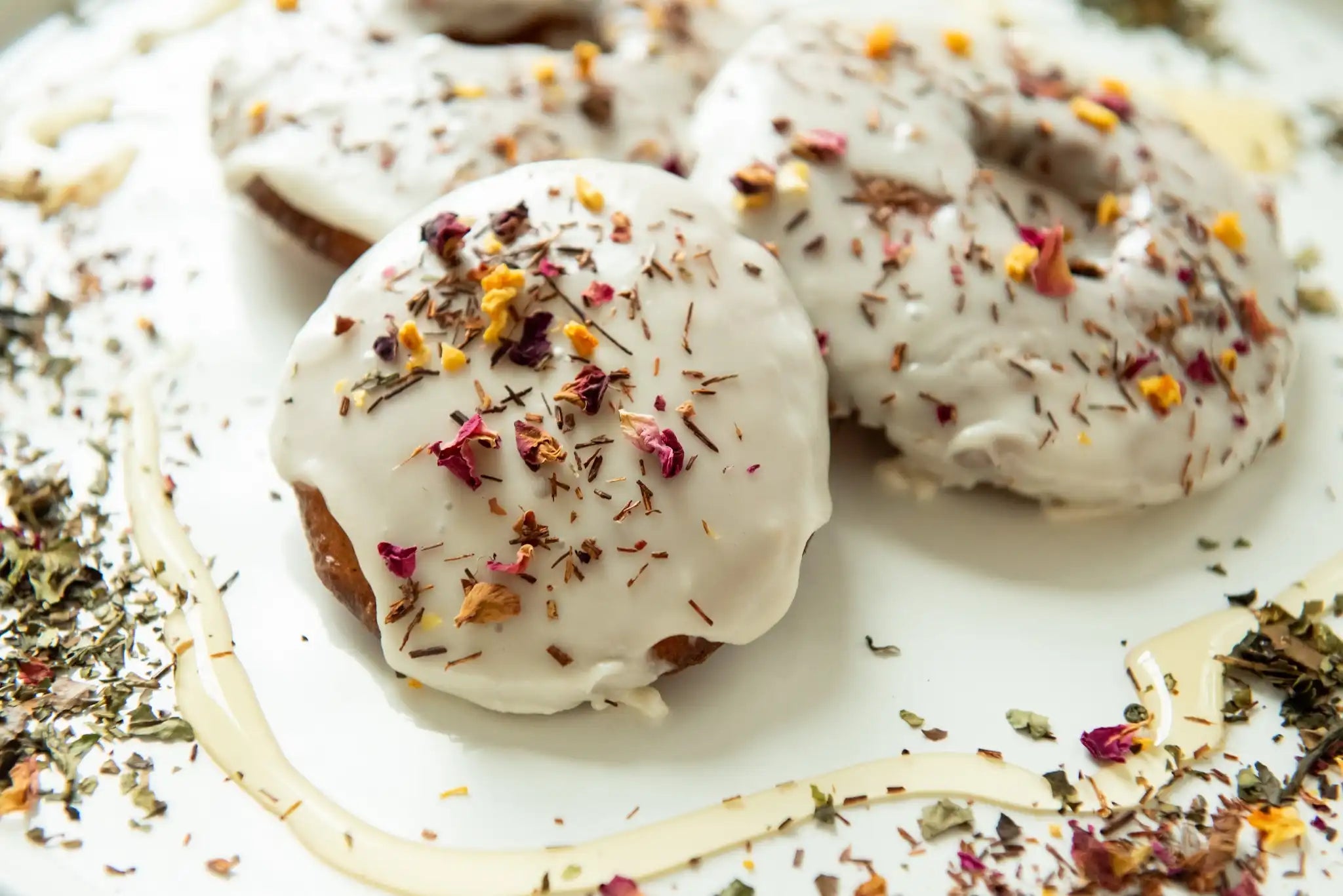 white glazed round donuts drizzled with honey and sprinkled with Egyptian Goddess loose leaf herbal tisane