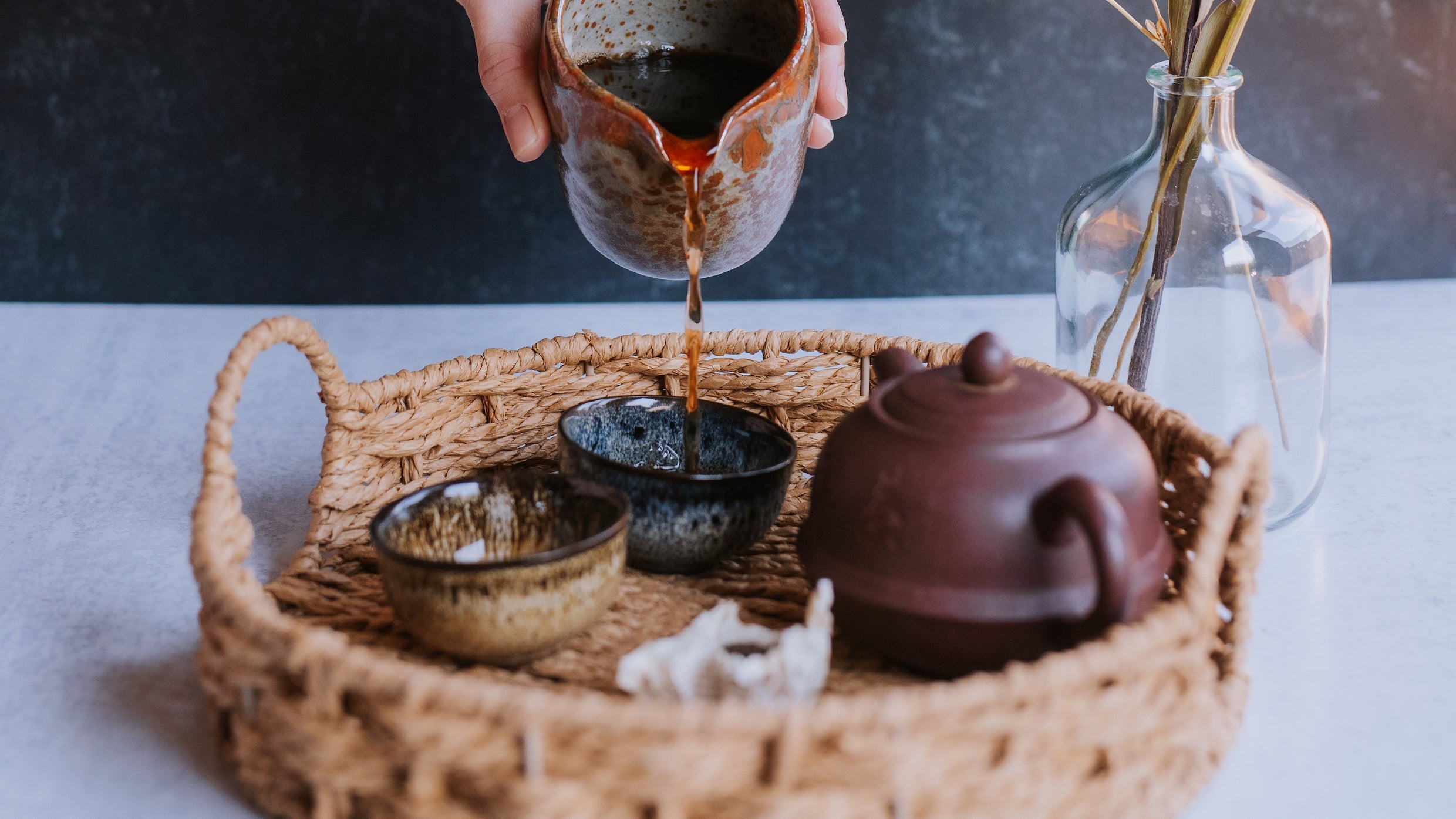 aged tea 2012 Menghai shou pu erh being poured into cups from a ben suga pottery pitcher and brewed in a yixing clay teapot