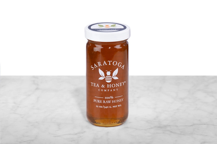 Amber NY wildflower honey in a 12oz clear glass jar branded with the Saratoga Tea & Honey Co. logo and a white top.