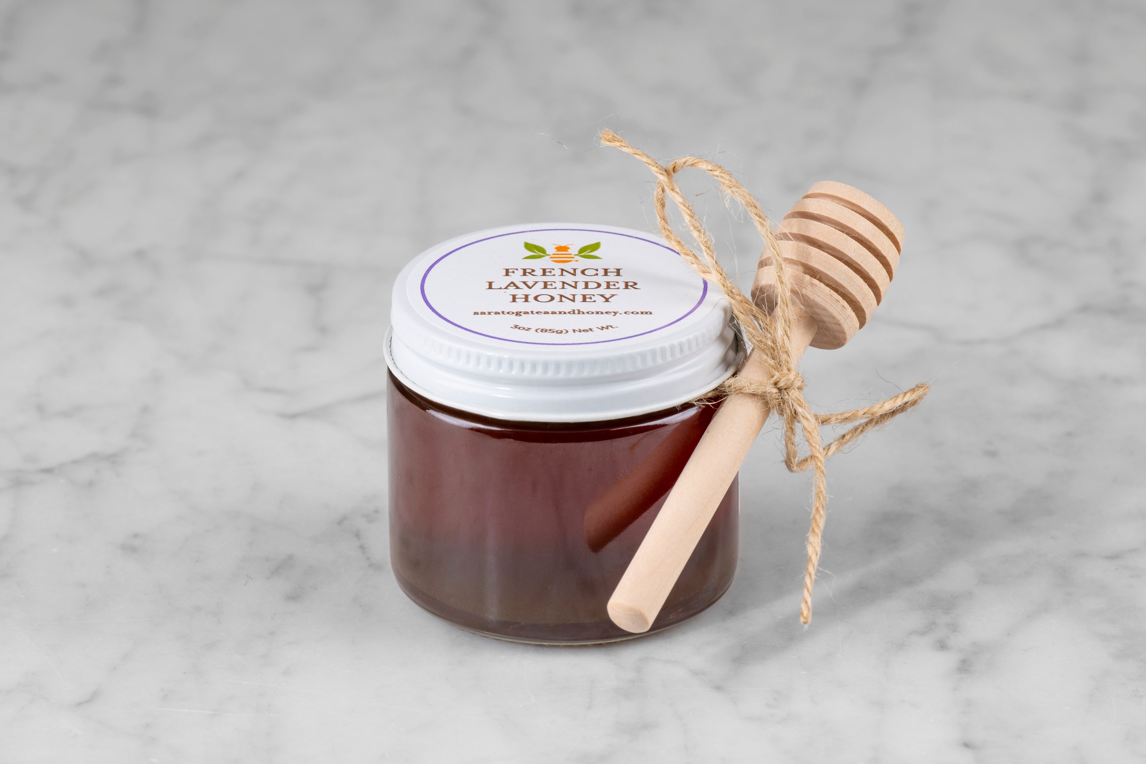 3oz jar of French Lavender Honey with twine and mini dipper on a marble background