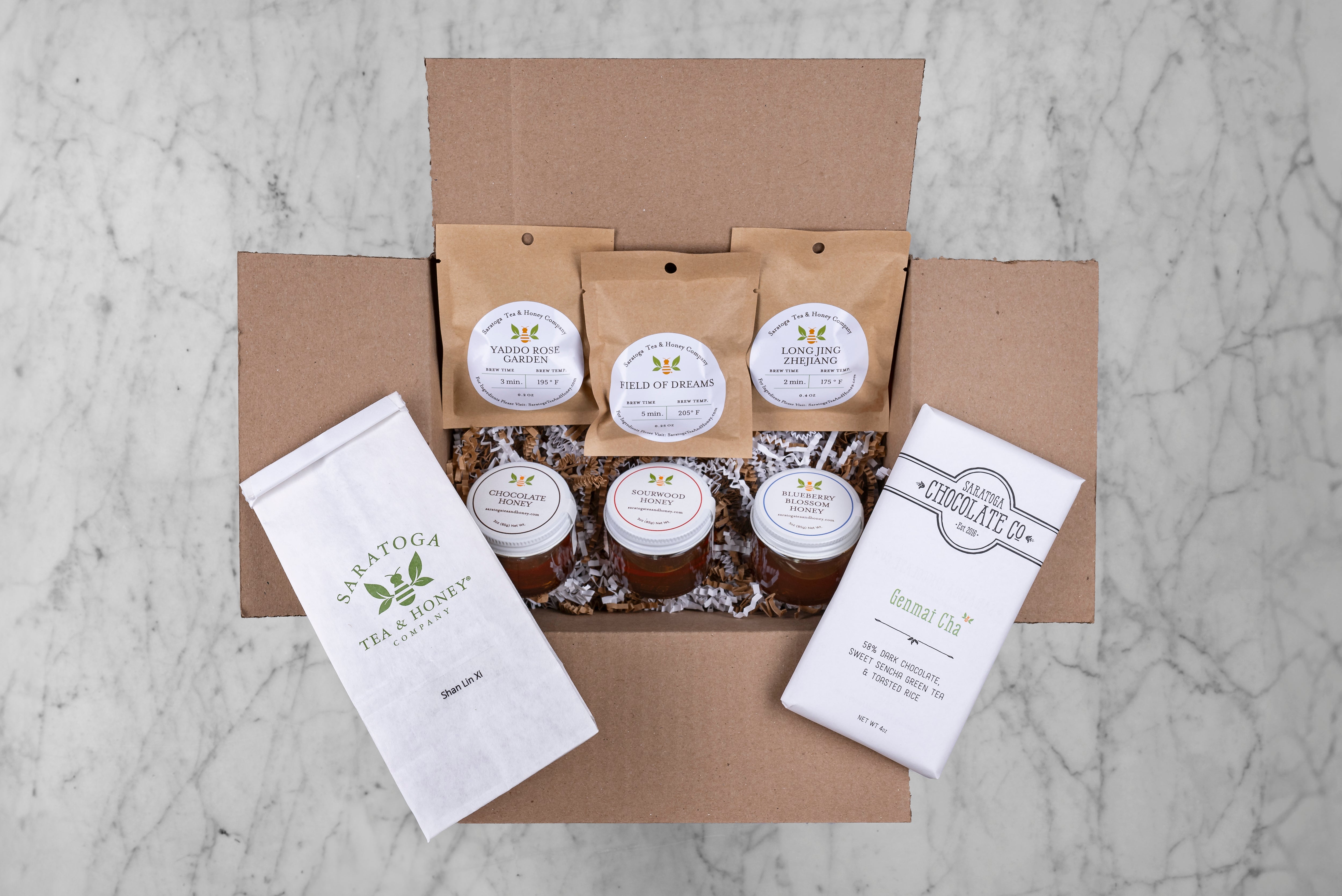 honey bee subscription tea and honey box from saratoga tea and honey featuring three sample teas, 3 sample honeys, a 2oz bag of tea and a local treat