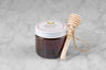 3oz jar of Italian Chestnut Honey with twine and mini dipper on a marble background