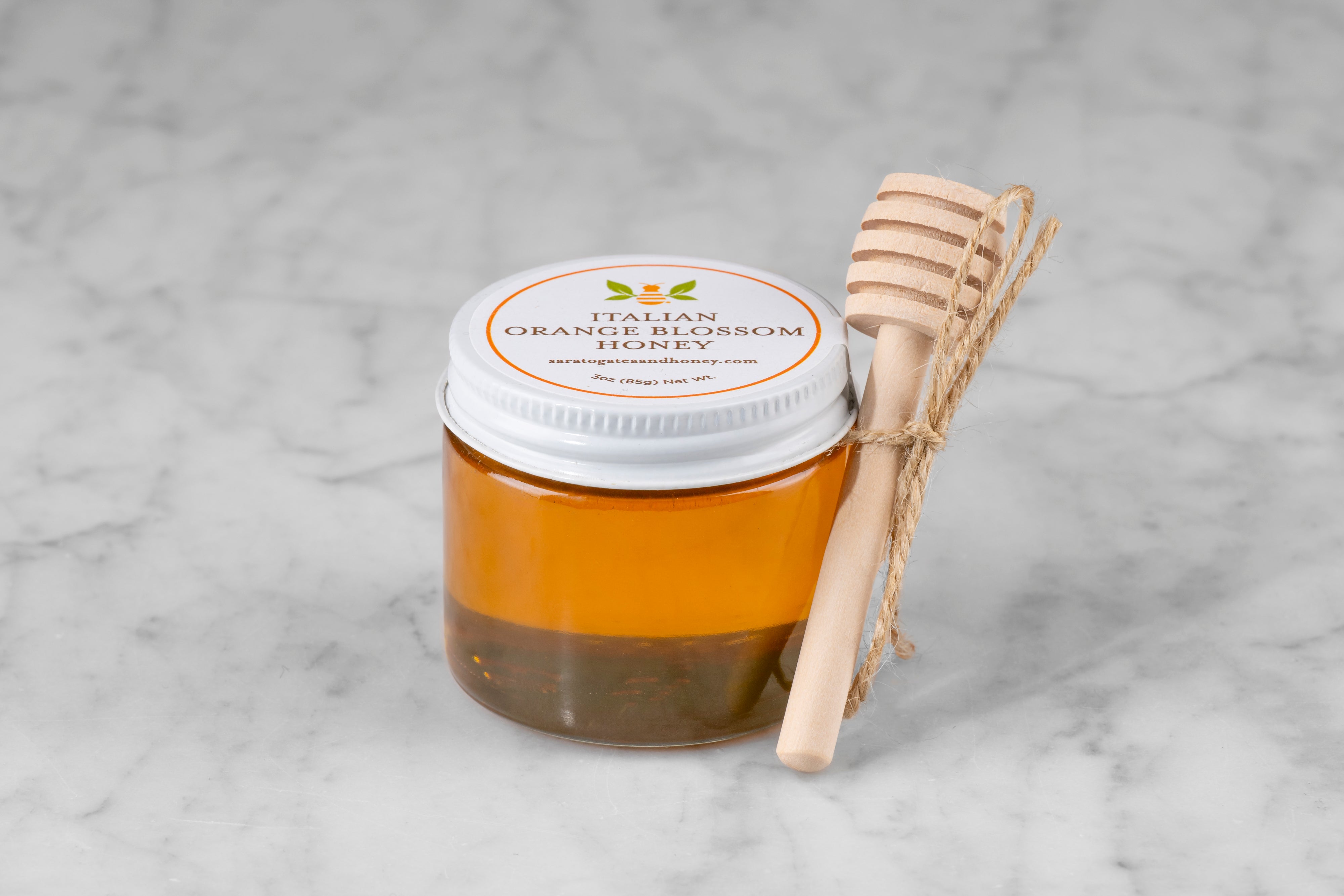 3oz jar of Italian Orange Blossom Honey with twine and mini dipper on a marble background