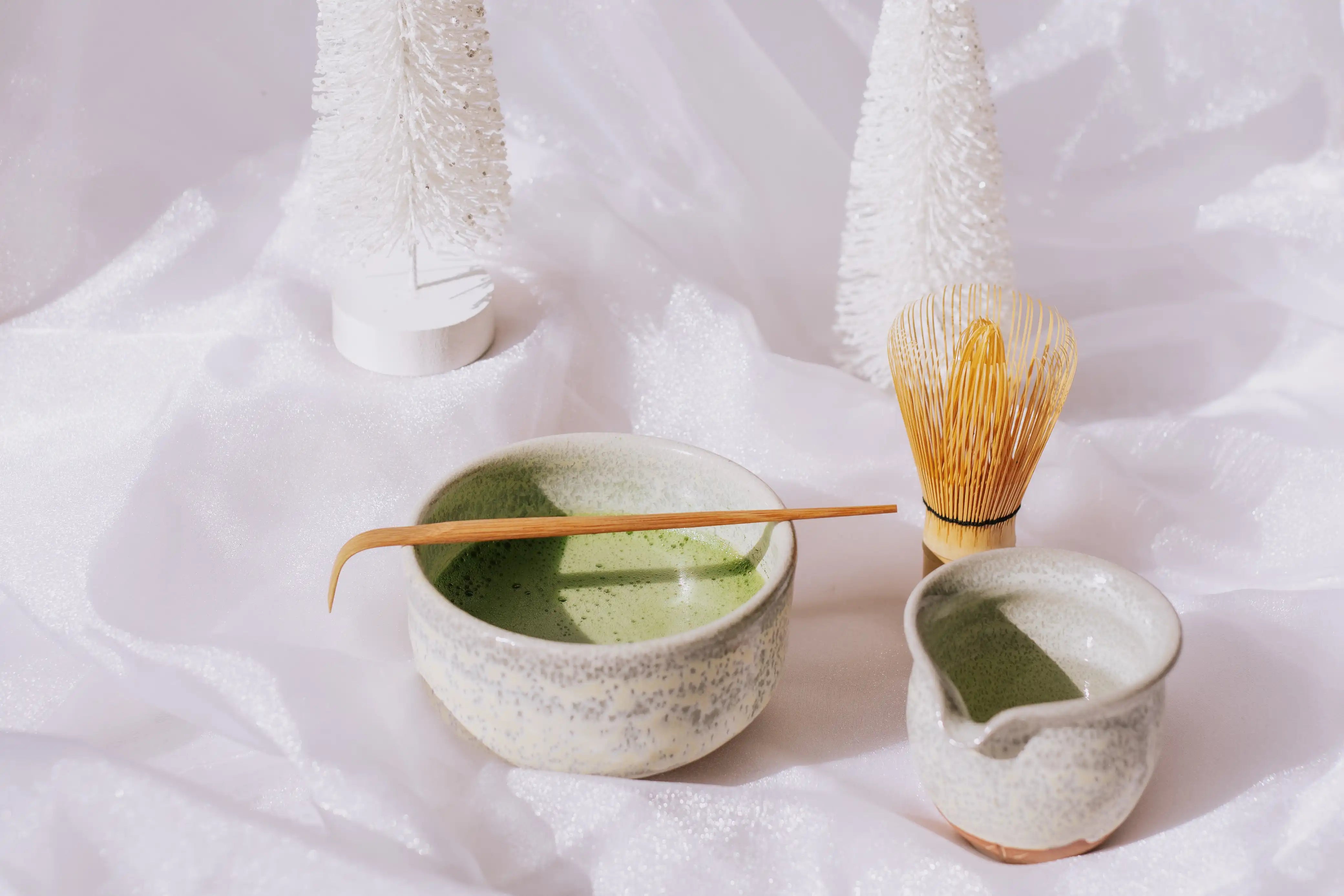 matcha in ben suga "snow" matcha bowl on a white background with matcha chasen and matcha bamboo scoop