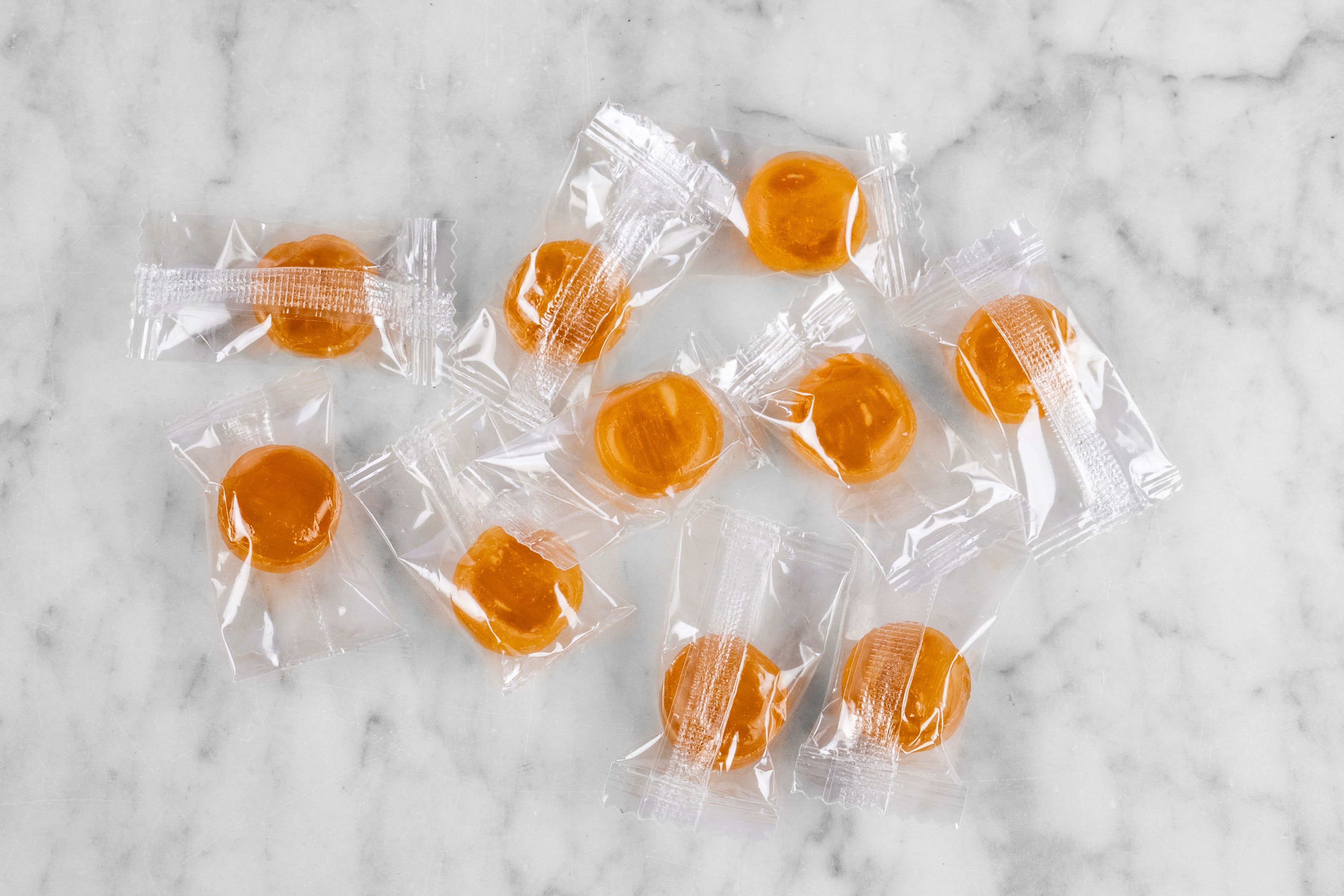 scattered manuka honey candies in wrappers on marble bacground