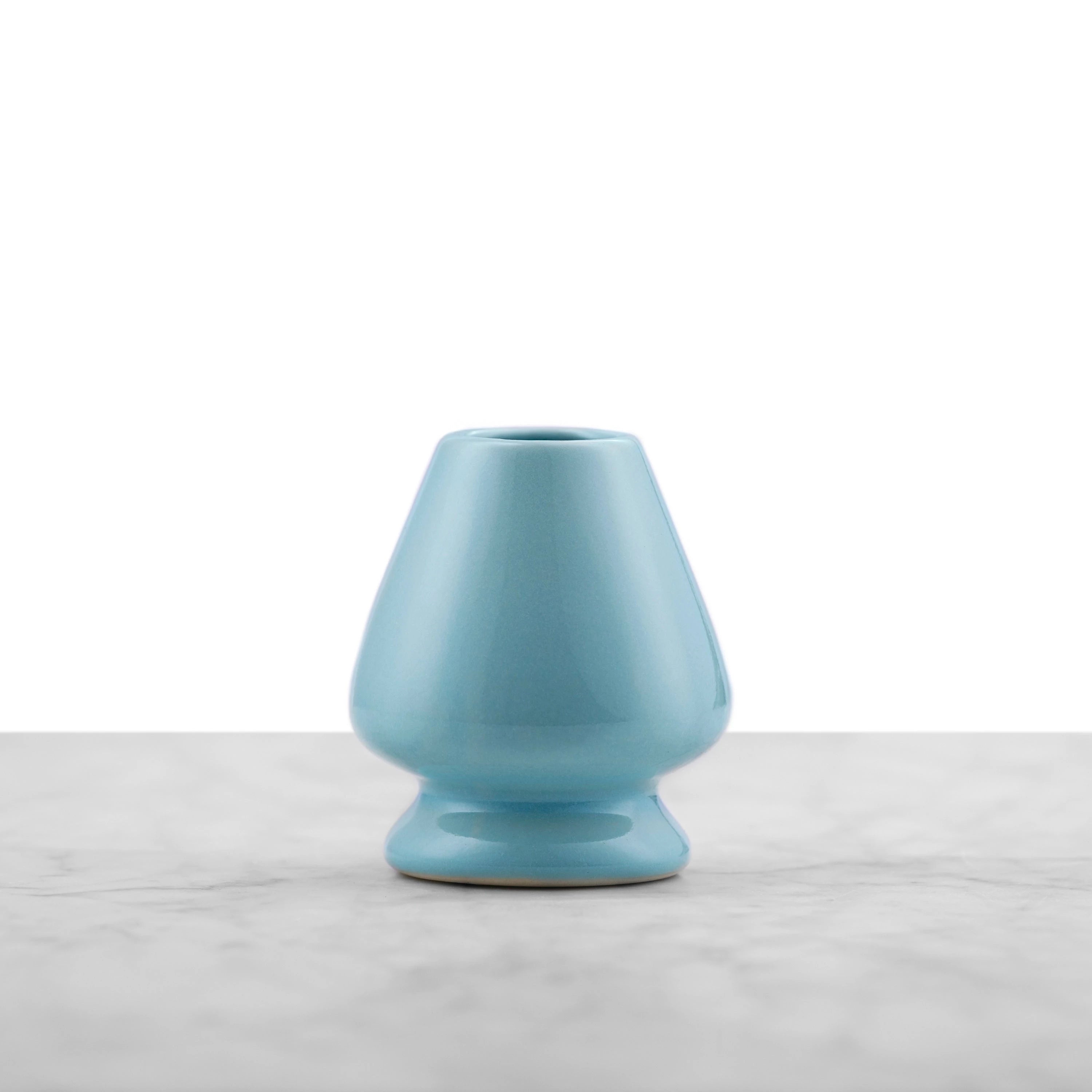 aqua colored ceramic matcha whisk stand in an tapered, rounded pyramid shape with a hole in the top center for the inner tines of the matcha whisk