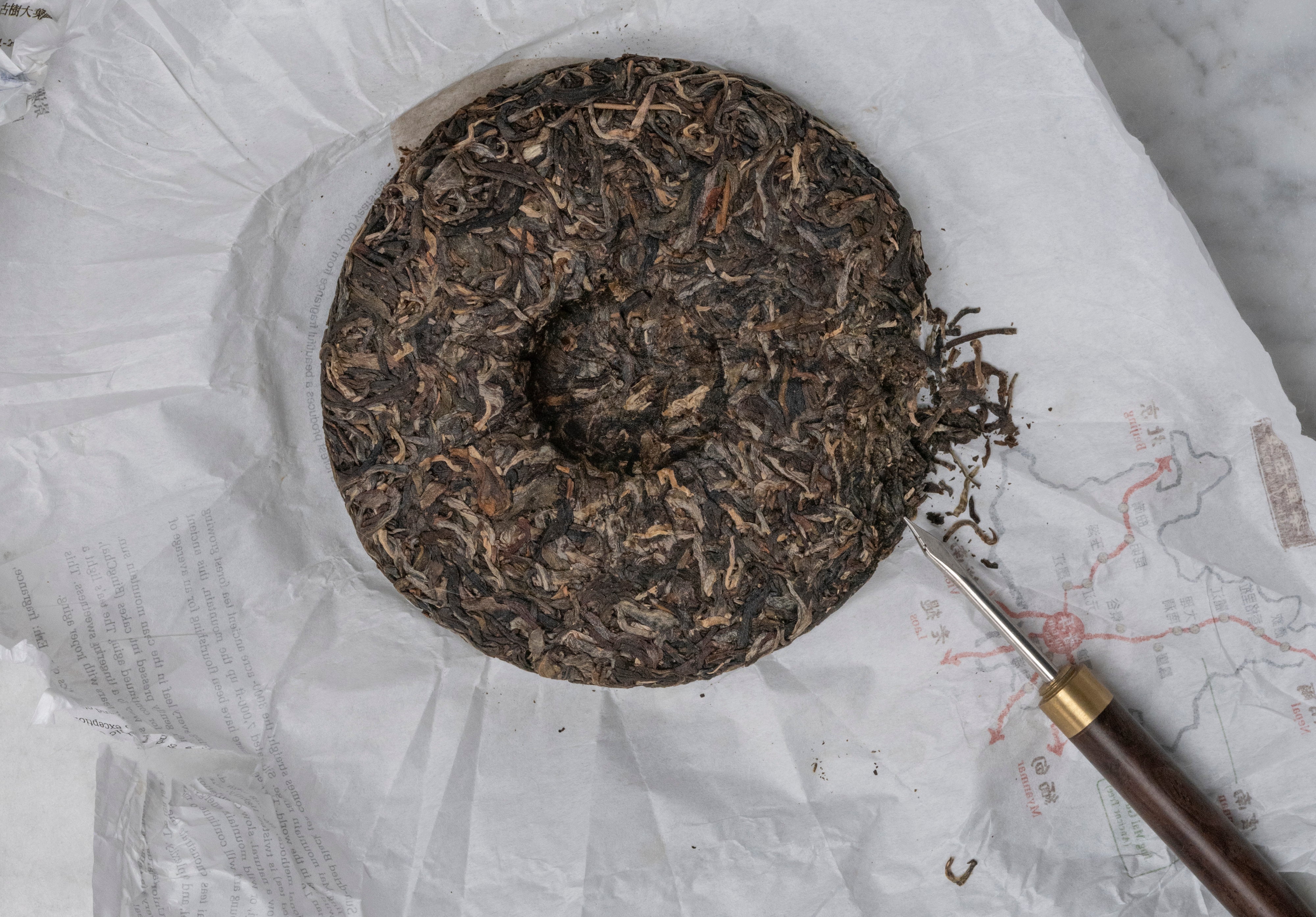 Unwrapped sheng pu erh old forest tea cake with tea needle