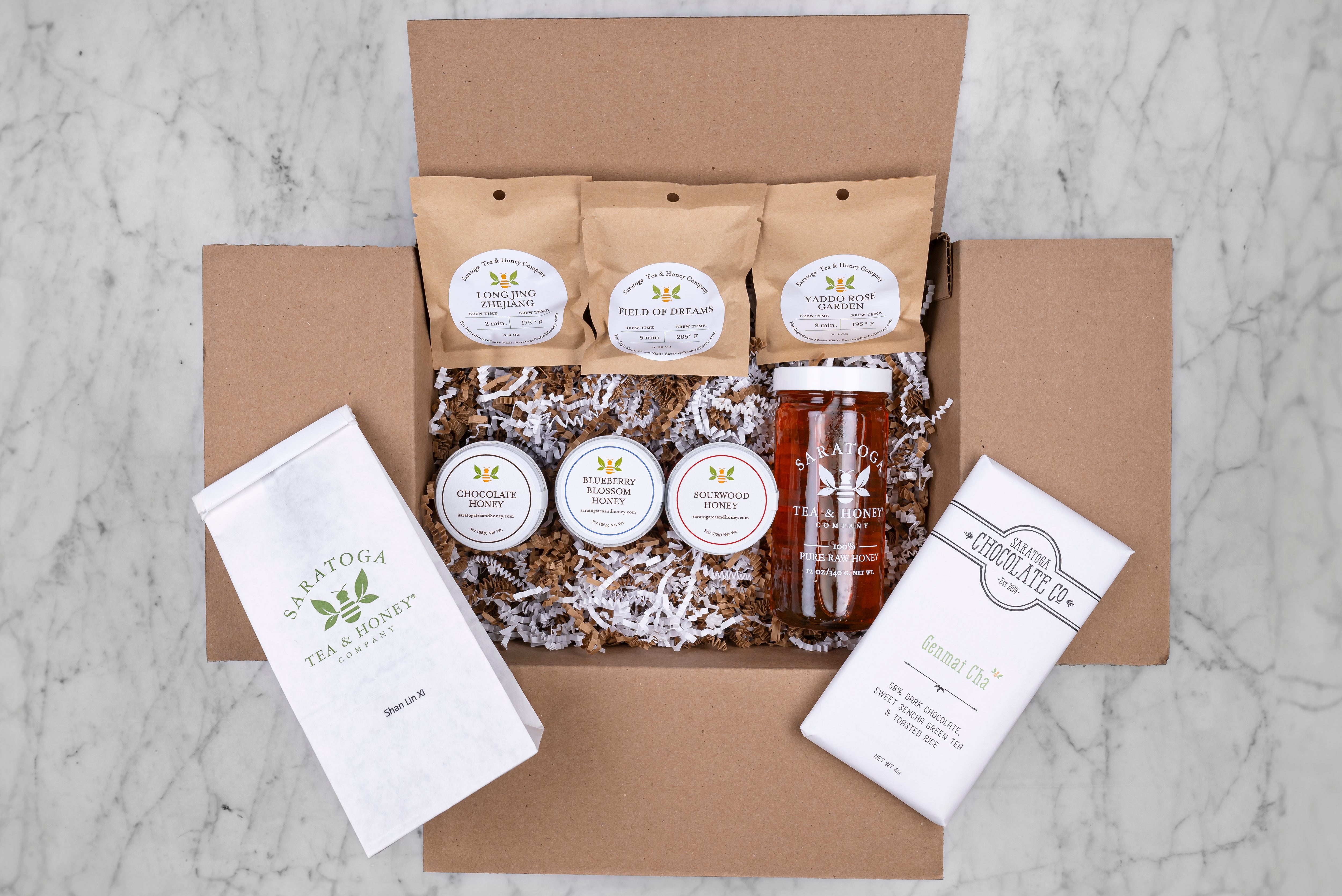 queen bee tea and honey subscription box from Saratoga Tea & Honey co featuring three sample teas, three sample honeys, a full size bag of tea, full size European honey and local treat