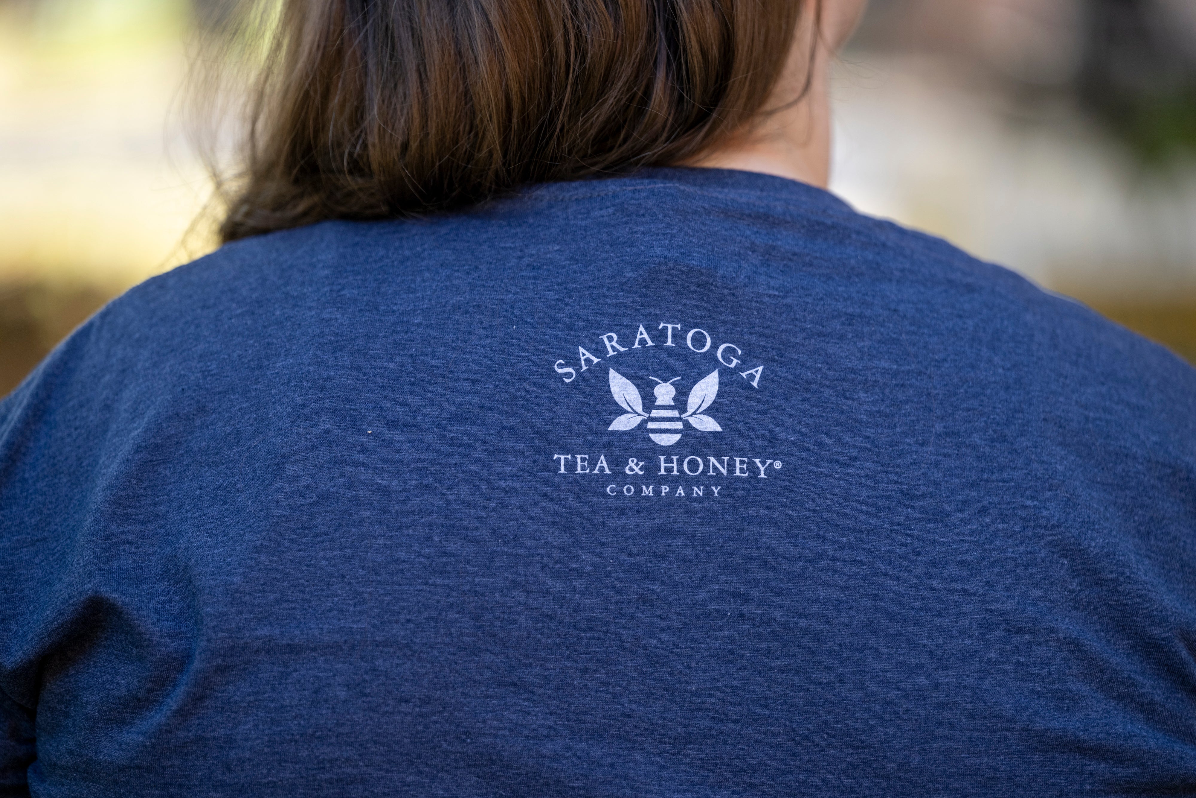 Saratoga Tea & Honey Co. logo on back of blue tshirt