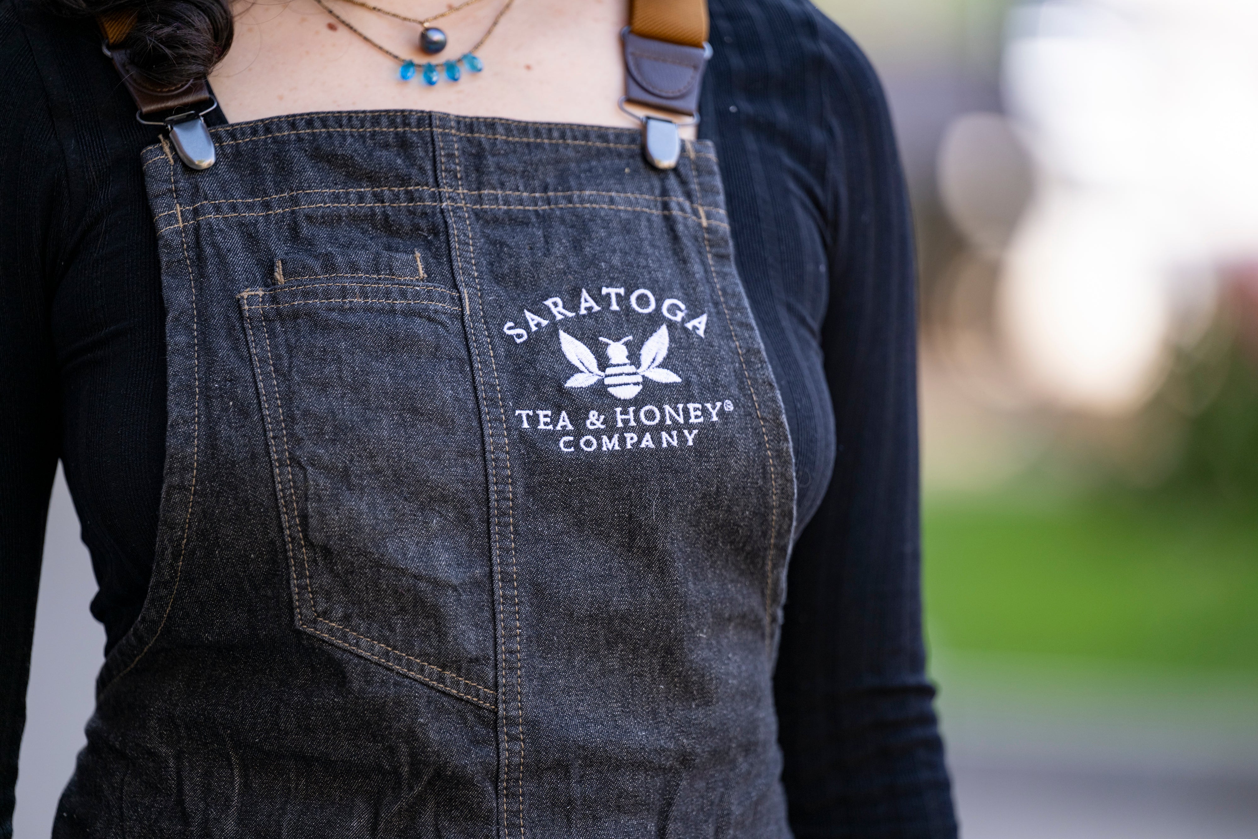 close up of Saratoga Tea & Honey Co logo embroidery on denim apron