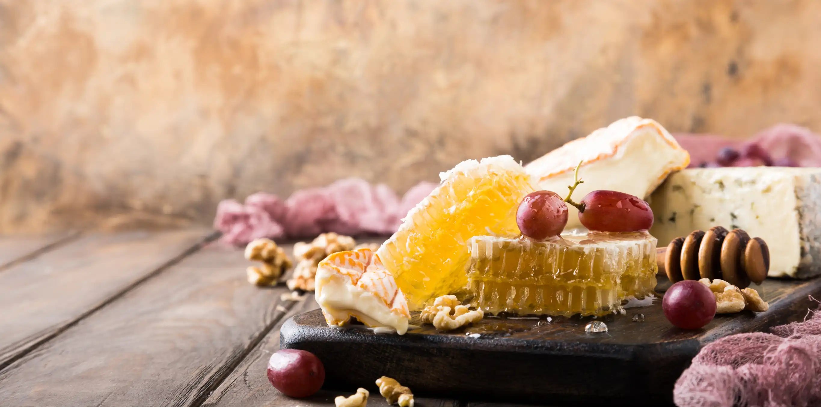 golden chunk honeycomb on a cheeseboard with grapes and several types of cheeses