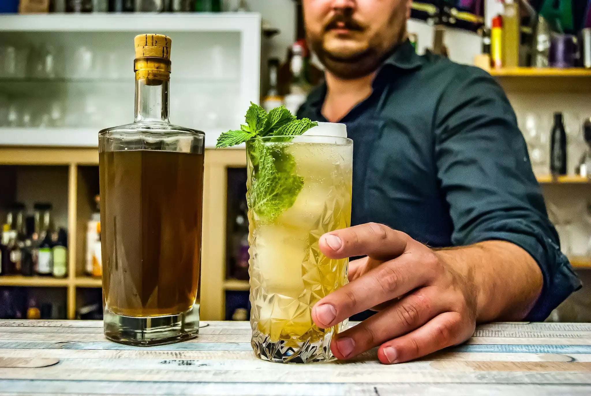 male bartender presenting mint julep cocktail