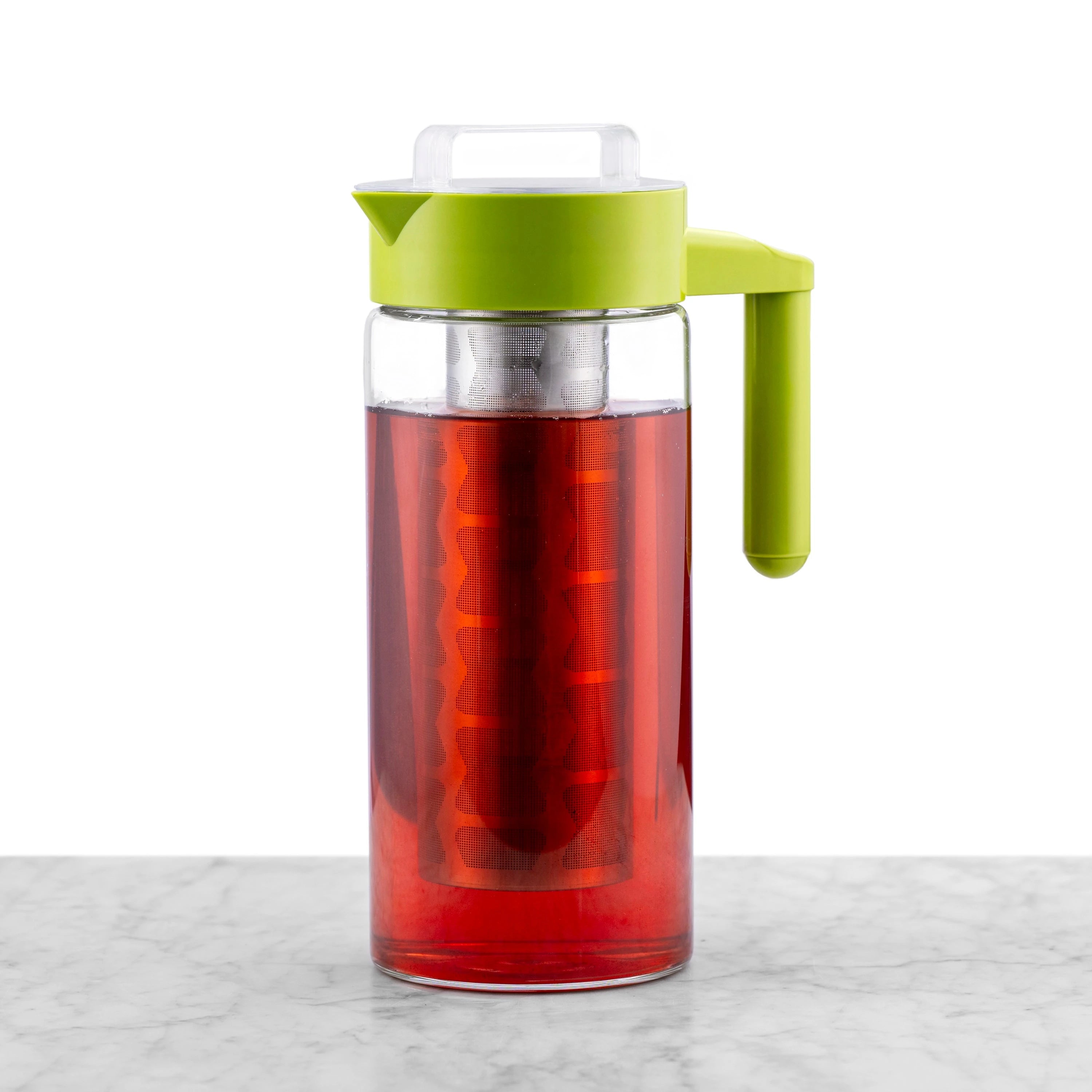 Clear glass cold tea maker filled with tea. Featuring a green handle and lid and a removable stainless steel mesh filter.